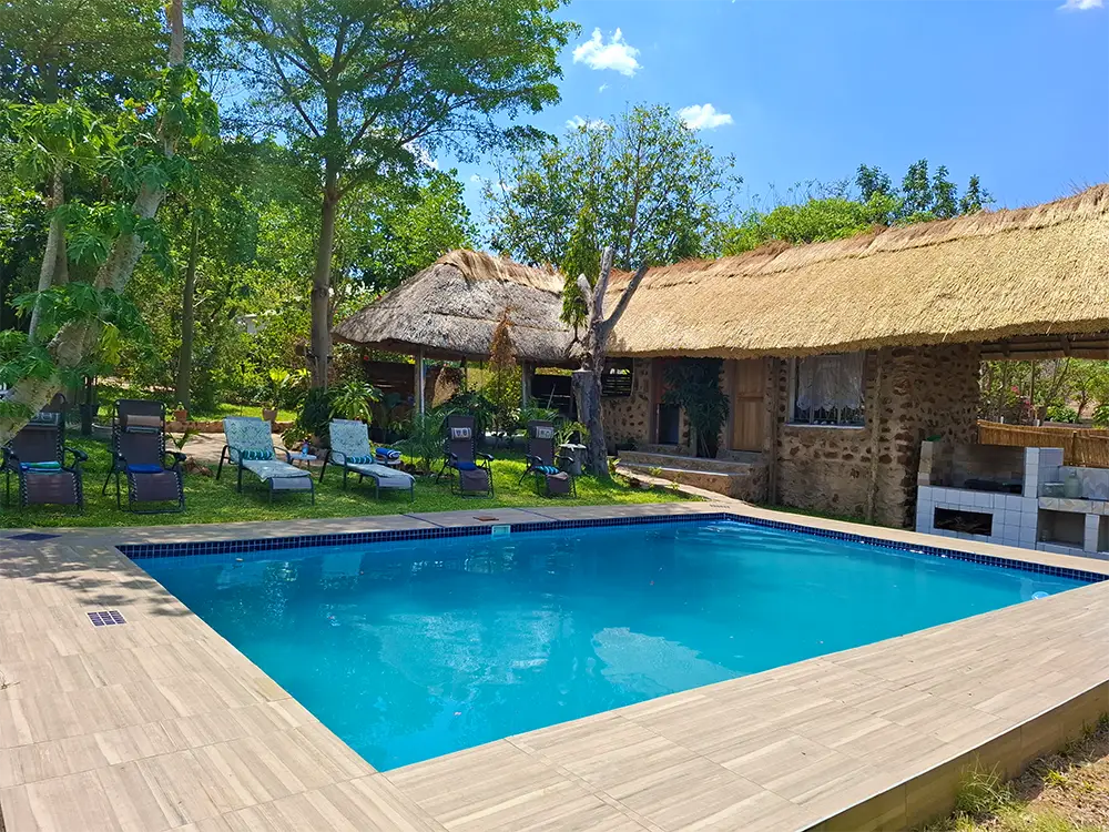 Swimming pool and sun loungers beside the thatched lapa
